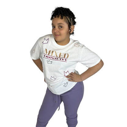 Biracial girl wearing a white shirt with 'MIXED ROYALTY' text with sparkly crown pattern and purple pants on a white background. 