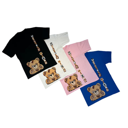 Flat lay of Four t-shirts in black, white, pink, and blue with teddy bear graphics and vertical stamp letters 'Uniquely Mixed' on a white background
